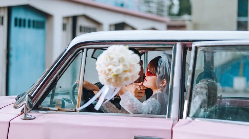 粉色复古婚车中的新婚夫妇